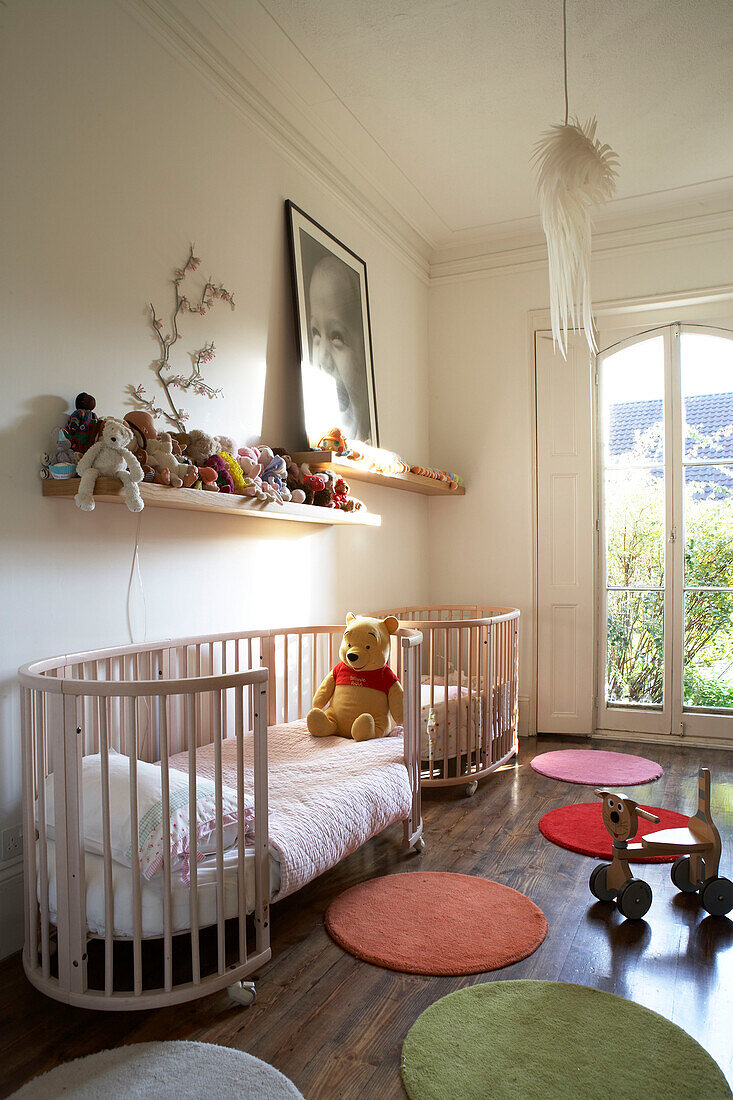 Modernes Kinderzimmer mit farbenfrohen runden Teppichen und einem großen Kinderbett