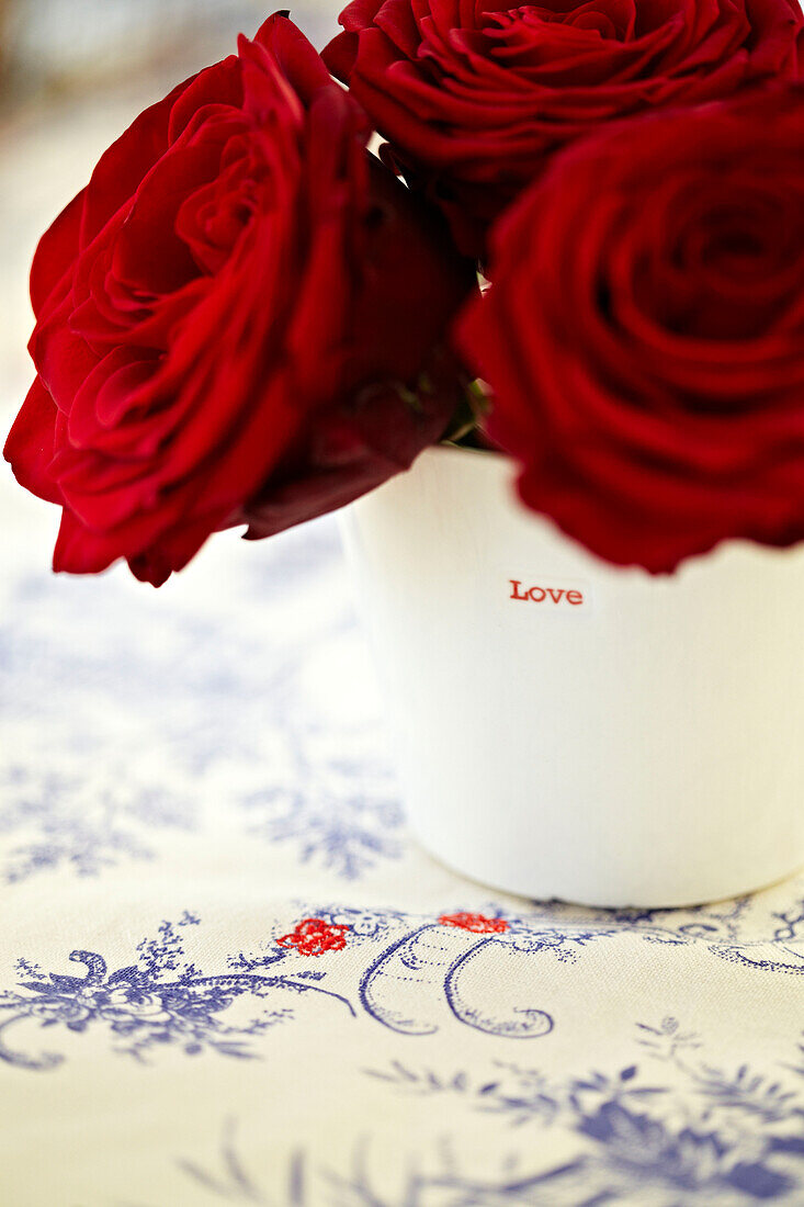 Rote Rosen auf einer bestickten Tischdecke