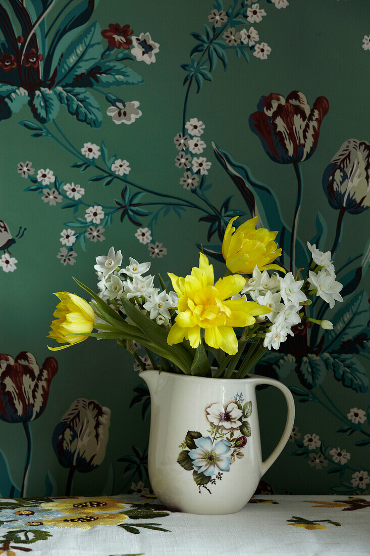Narzissen und Tulpen in einem Blumenkrug mit floralem Hintergrund