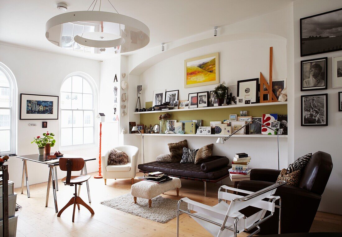 Modernes Wohnzimmer mit Regalen voller Kunstwerke und gewölbten Fenstern und Plexiglasleuchten