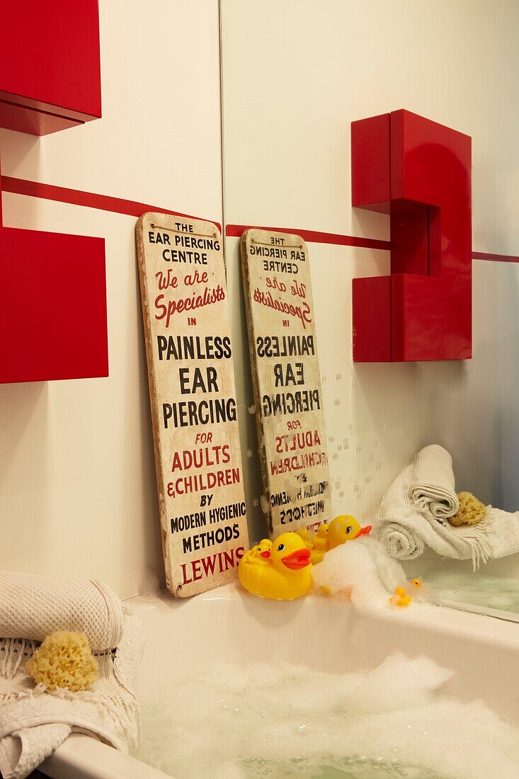 Bathroom detail with Ear Piercing sign and rubber duck and red cabinet