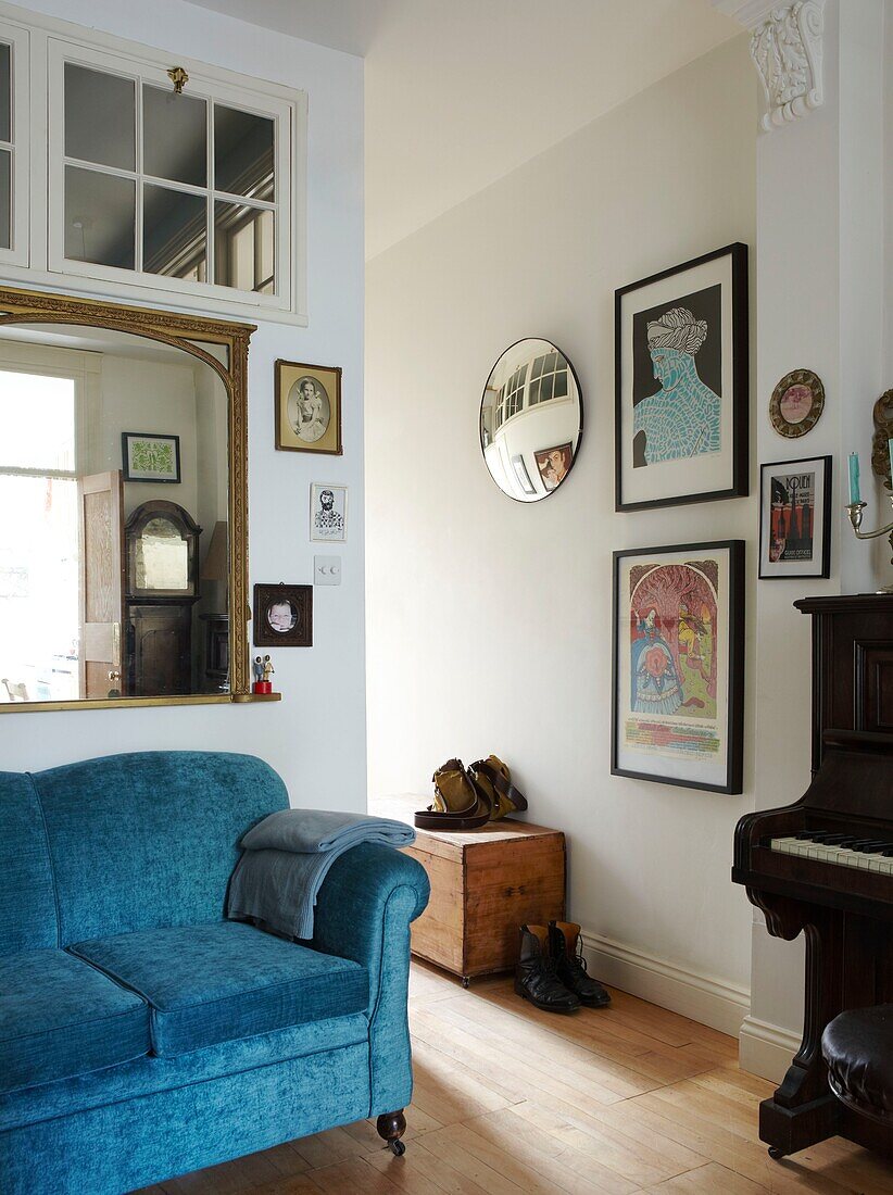 Spiegel mit vergoldetem Rahmen über dem Sofa im Eingangsbereich mit Kunstwerken und Klavier