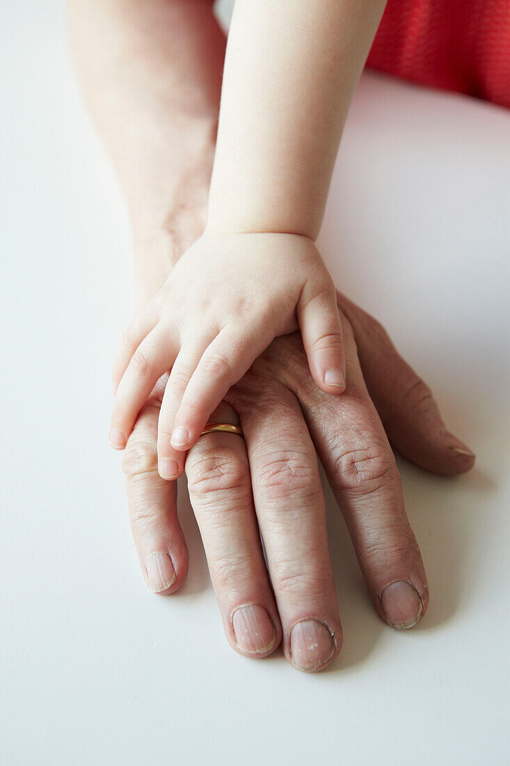 Hand eines dreijährigen Kindes auf reifer Erwachsenenhand