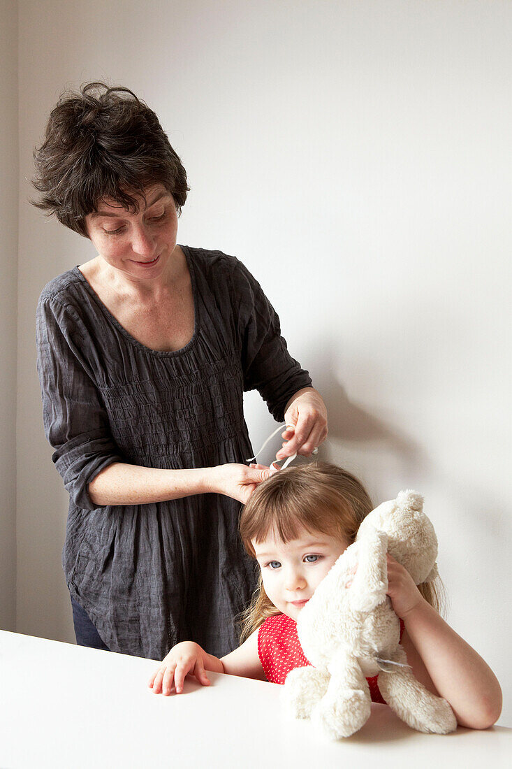 Mutter frisiert die Haare ihrer Tochter