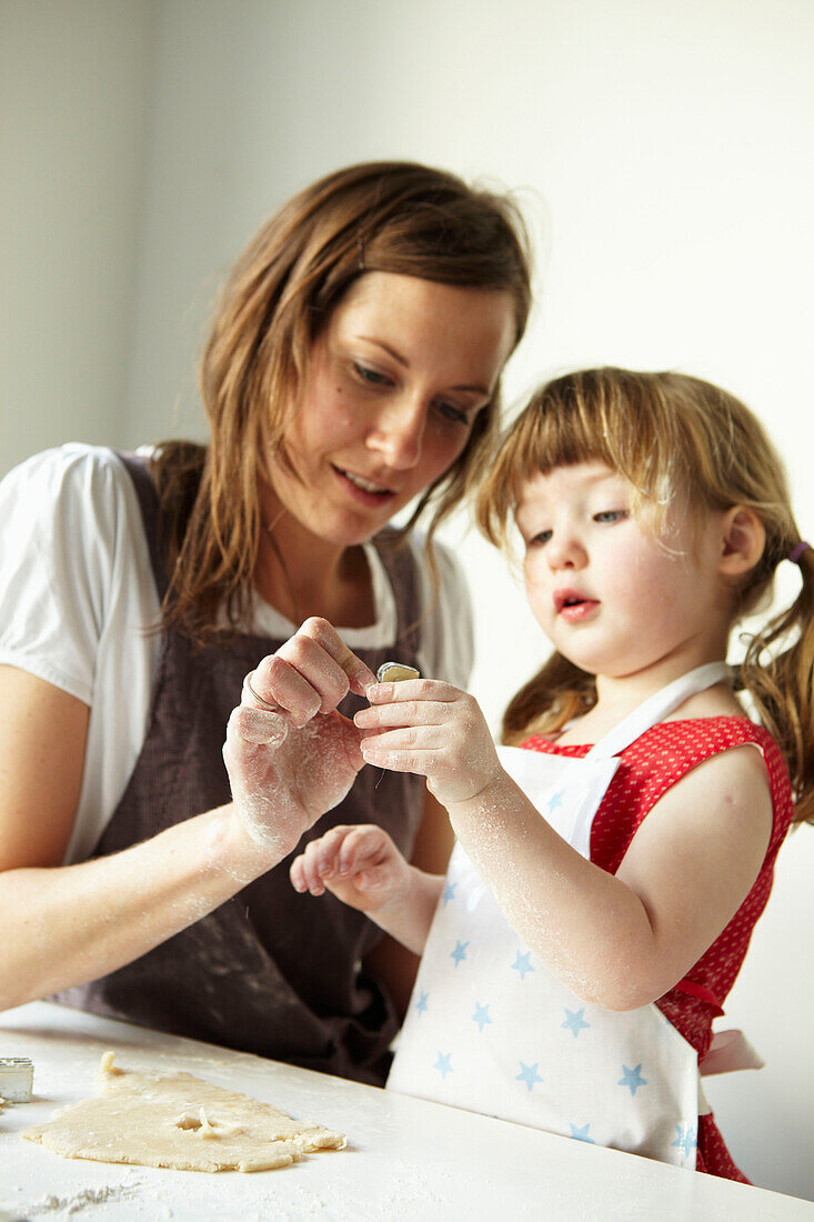 Mother and daughter cutting pastry together
