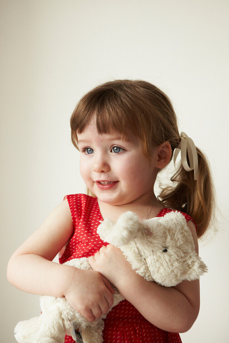 Young girl in red dress holding a teddybear