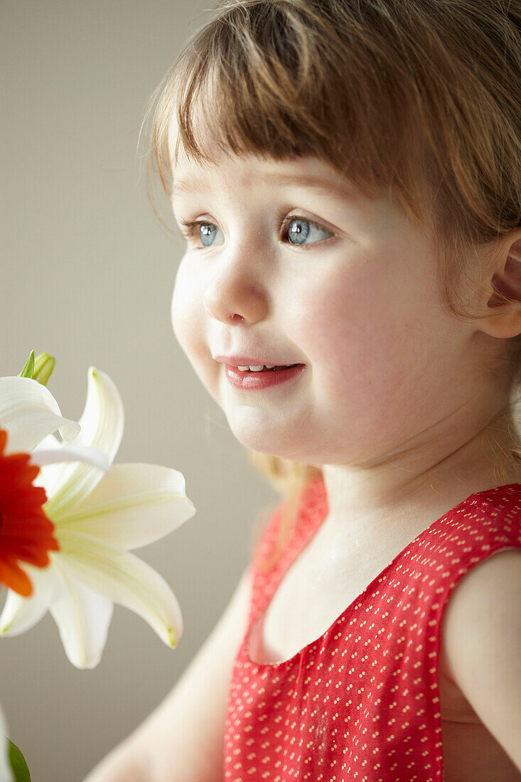 Drei Jahre altes Mädchen in rotem Kleid mit Schnittblumen