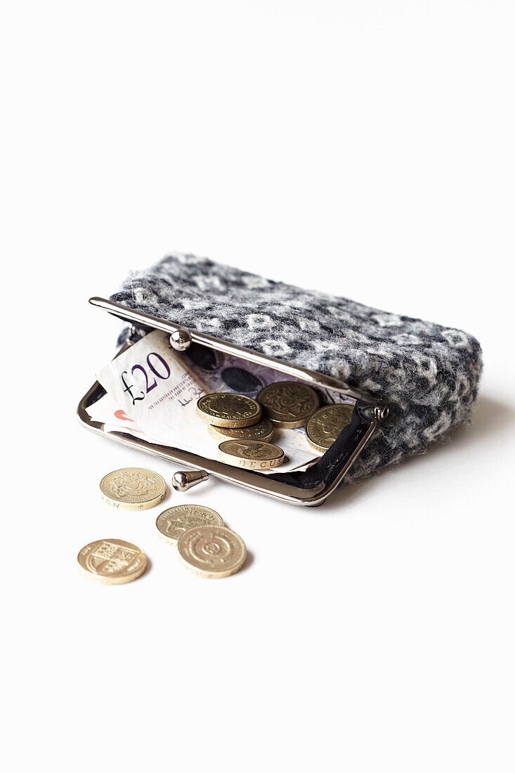 Pound coins and folded banknote in grey patterned purse