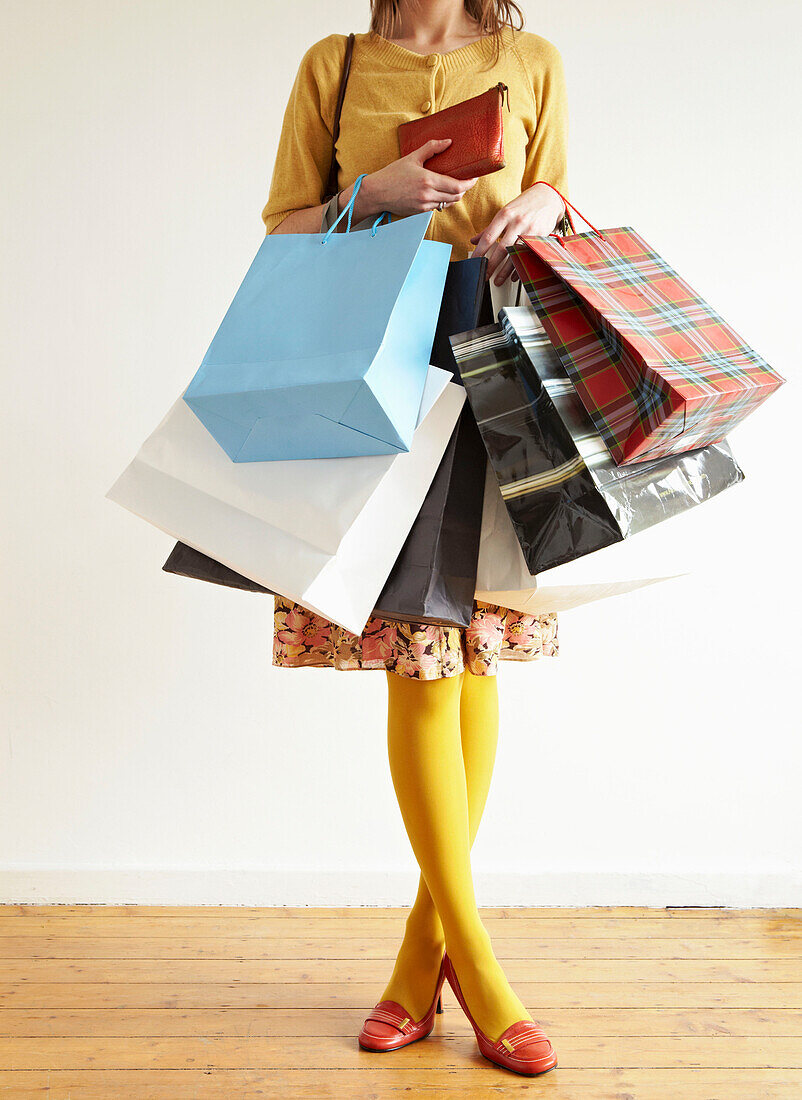 Woman stands holding an assortment of shopping bags