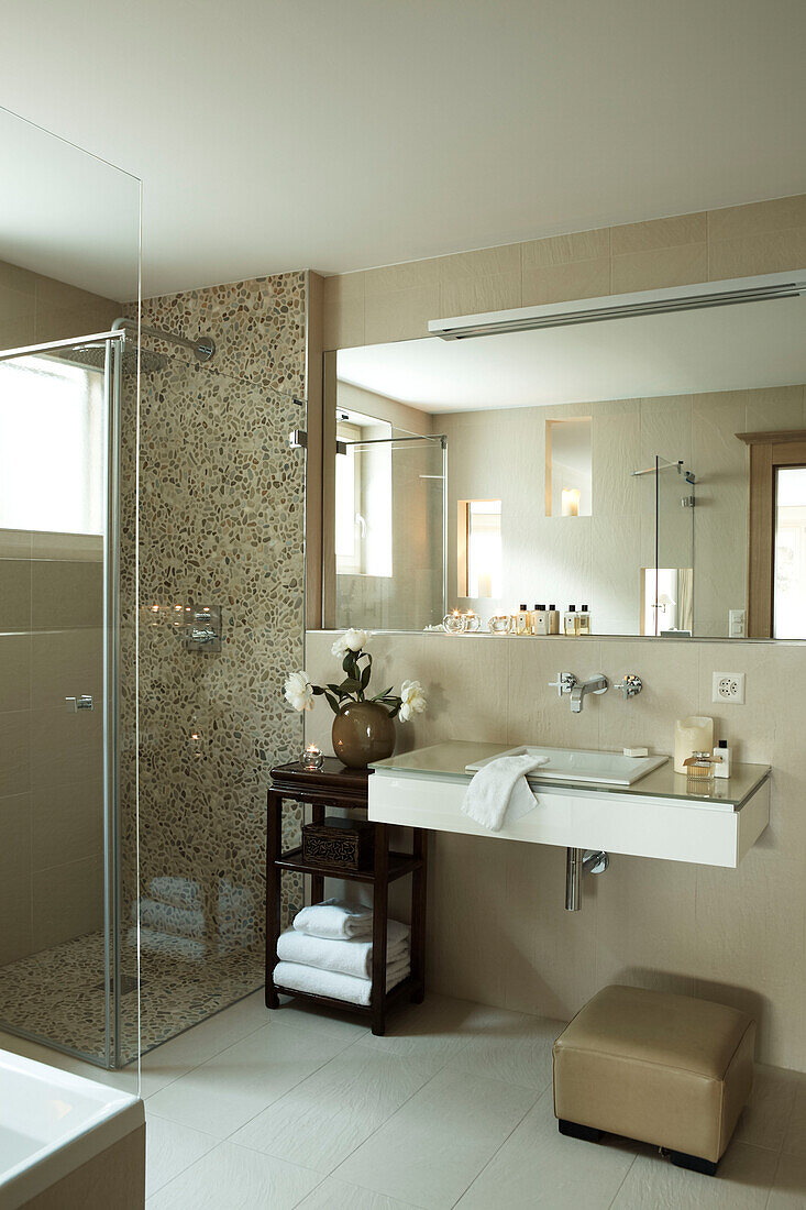 Large mirror above washbasin with shower cubicle in luxury Zermatt home, Switzerland