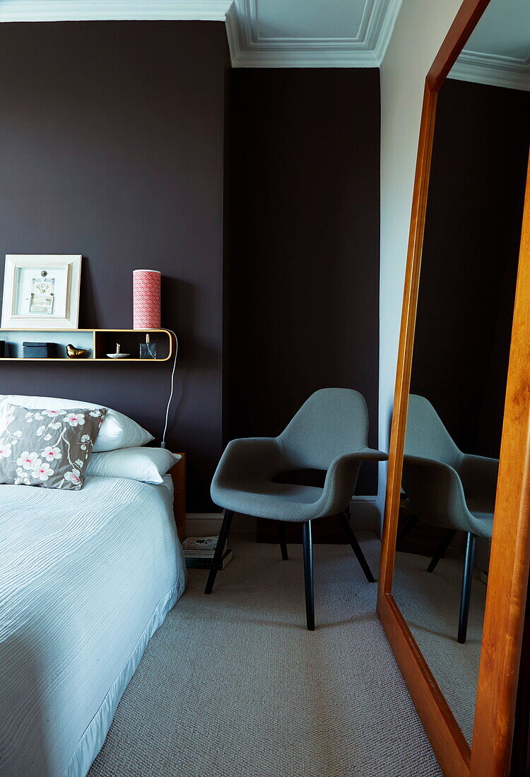 Großer Spiegel und grauer Stuhl am Bett in einem Londoner Stadthaus, England, UK