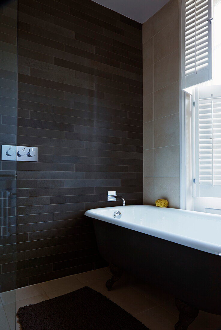Gefliestes Badezimmer mit Roll-Top-Badewanne in einem Londoner Stadthaus, England, UK