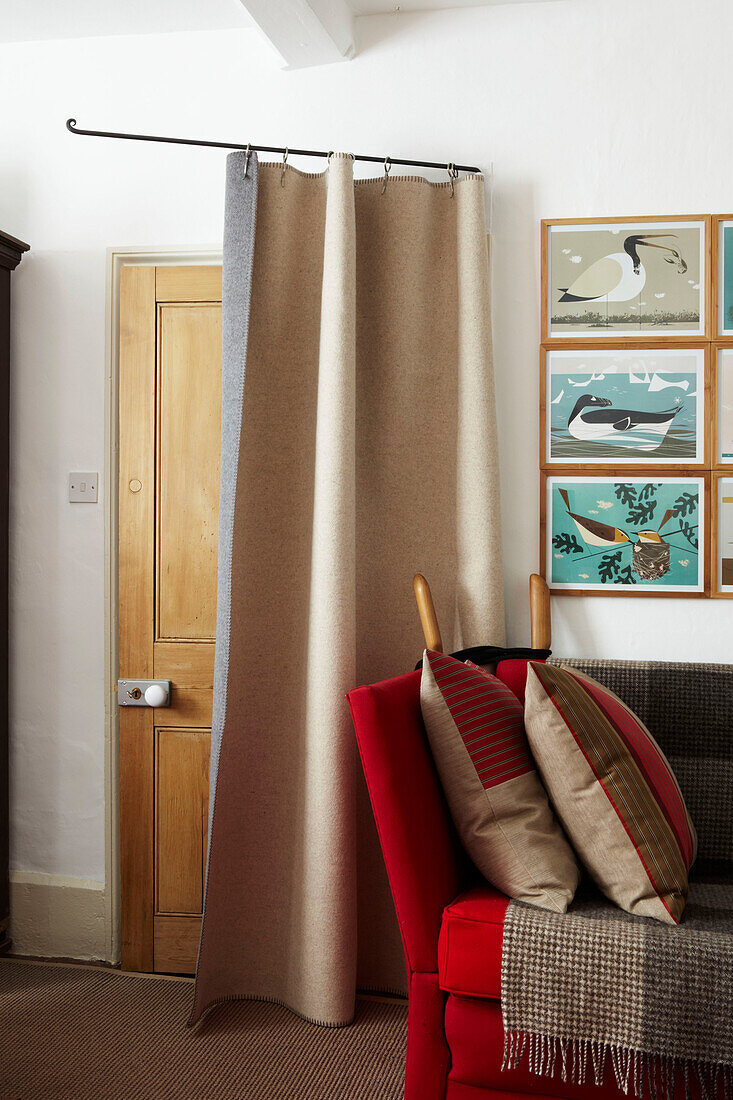 Living room entrance doorway with draft excluder curtain and sofa with rugs and cushions