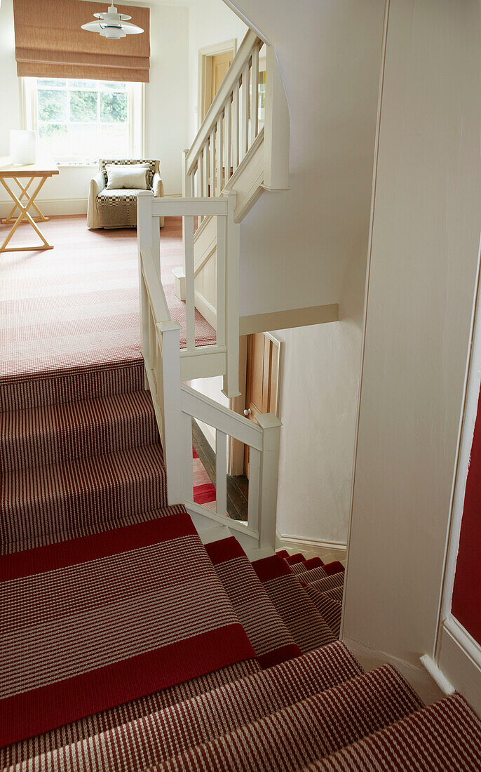 Treppe und Treppenabsatz im Obergeschoss mit gestreiftem rotem Teppich