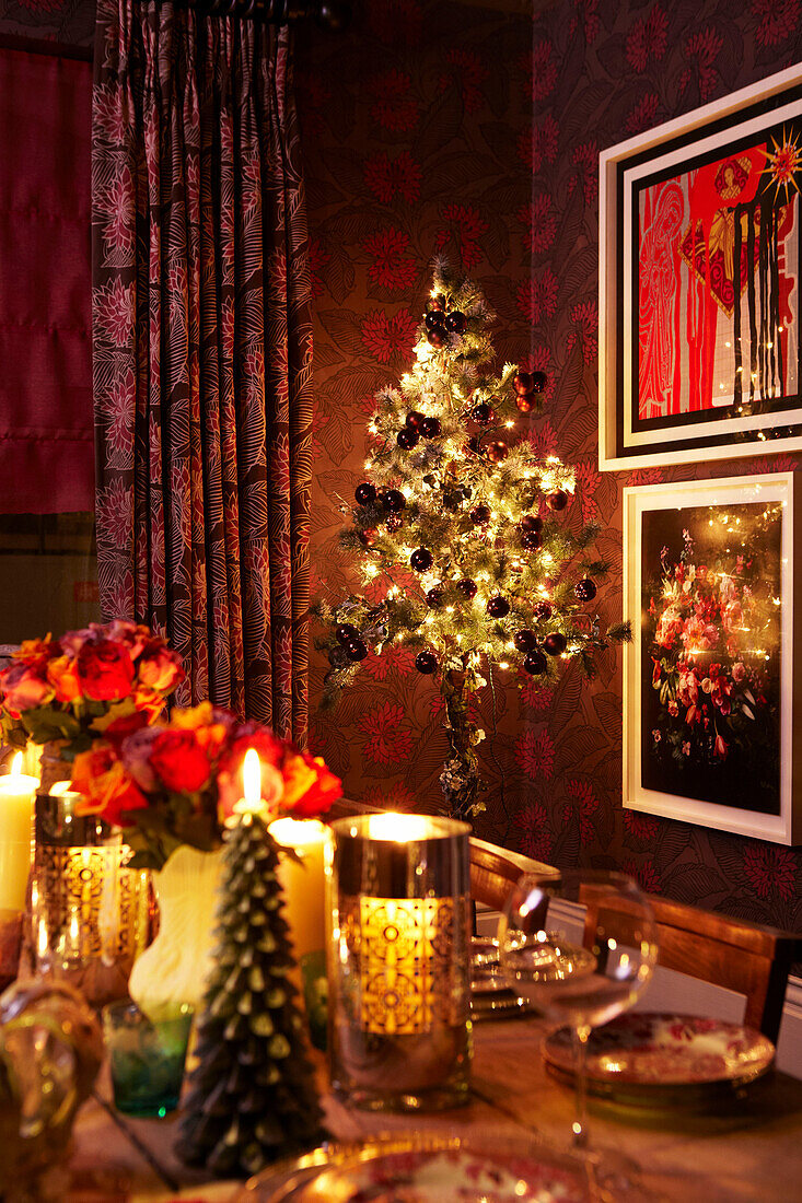 Bunt gedeckter Weihnachtstisch in Rot und Gold mit Rosen, Kerzenlicht und Weihnachtsbaum