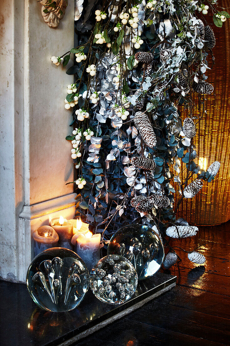 Detail des Kamins mit festlicher Girlande, Kerzen und Briefbeschwerern aus Glas auf der Feuerstelle