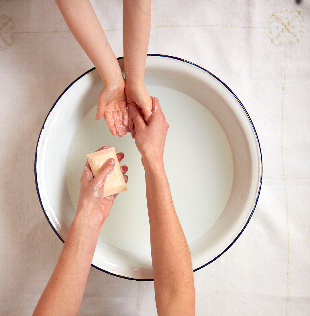 Mother and child washing hands in a bowl