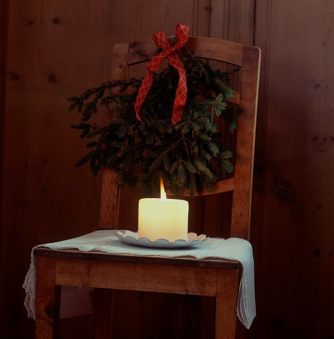 Holzstuhl mit brennender Kerze und Weihnachtskranz