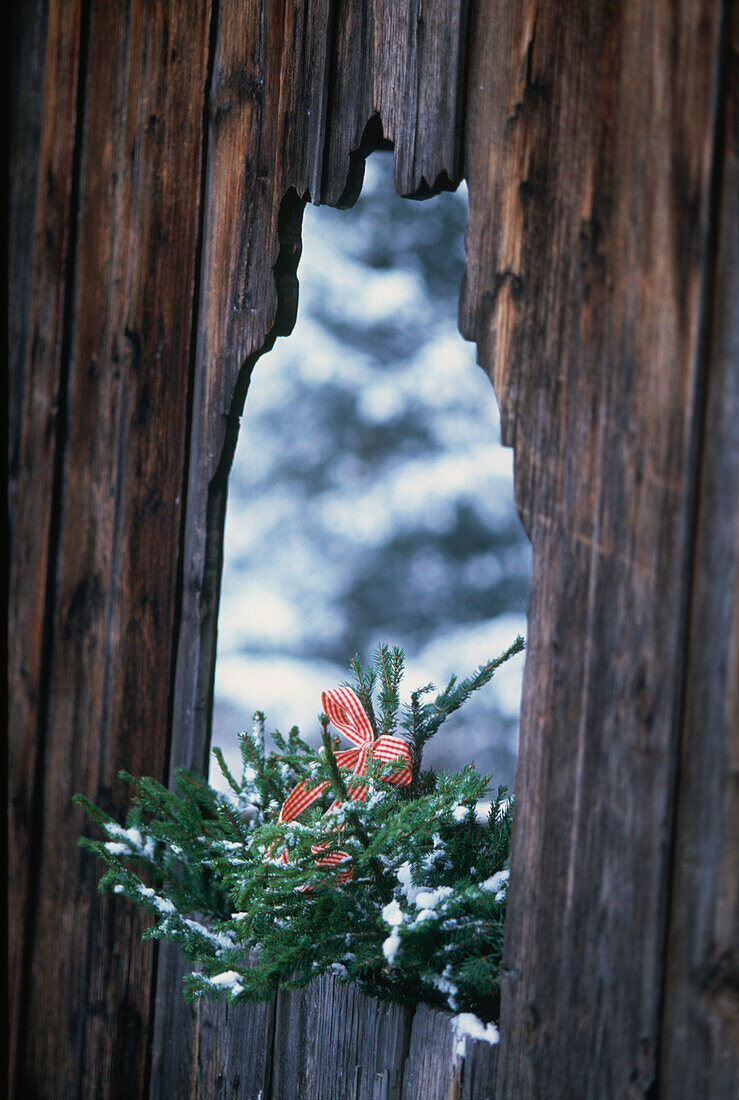 Snowy landscape through wooden door with Christmas wreath in the Dolomite mountains