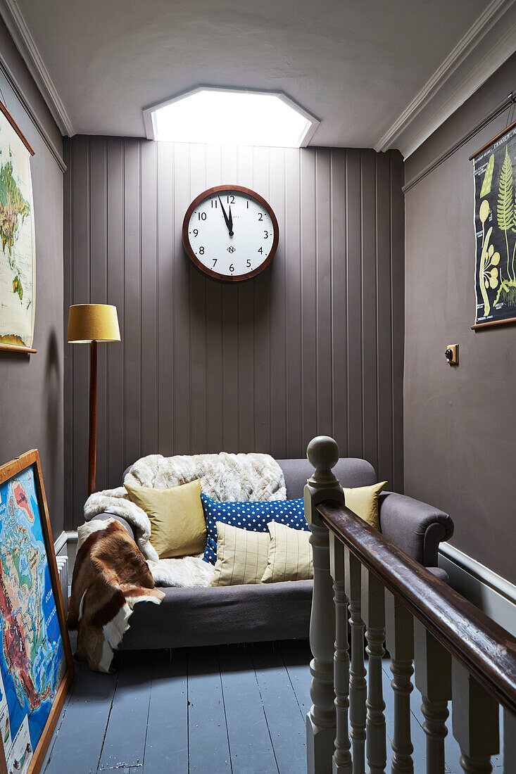 Oberlicht über einer Uhr mit Zweisitzer-Sofa im Flur eines Familienhauses in Rye, East Sussex, England, UK