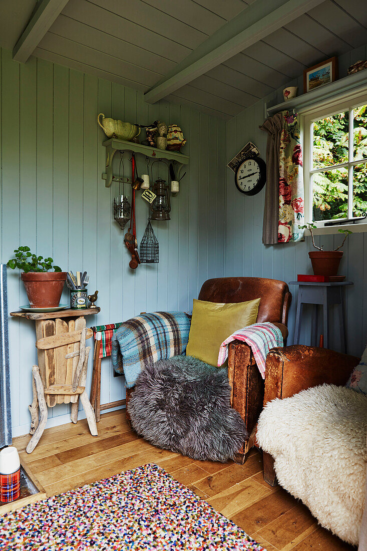 Brauner Ledersessel mit Fellüberwurf in getäfeltem Sommerhaus in Rye, East Sussex, England, Vereinigtes Königreich