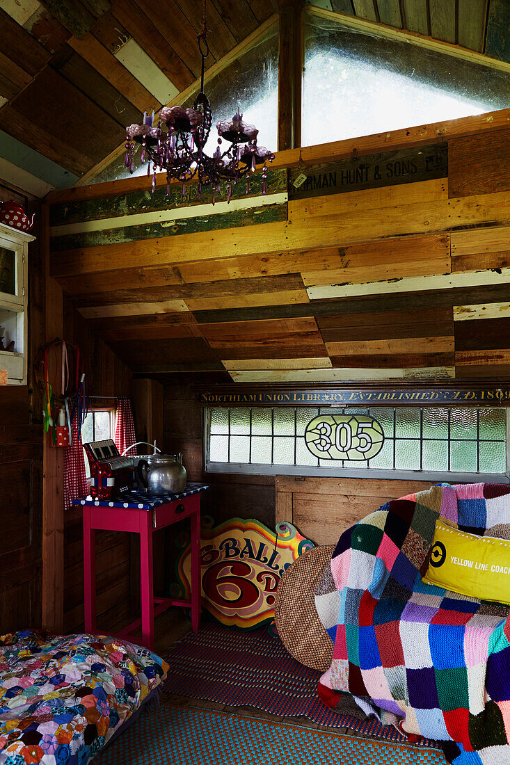 Bunte Patchwork-Decken und Holzdecke in einem Baumhaus, East Sussex, England, UK