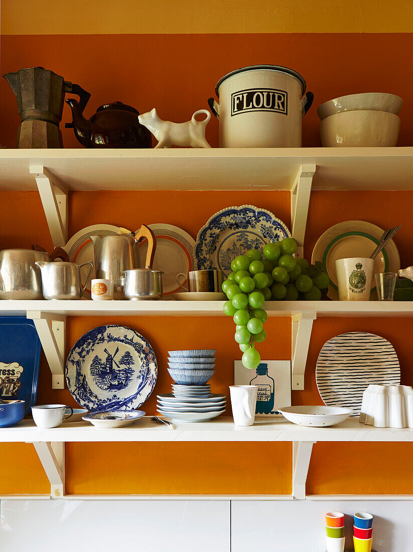 Assorted kitchenware on white open shelves in Hackney kitchen, East London, UK