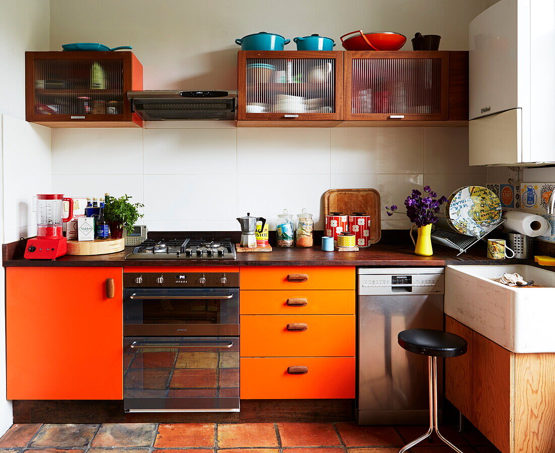 Orange retro-fitted kitchen in colourful London home, England, UK