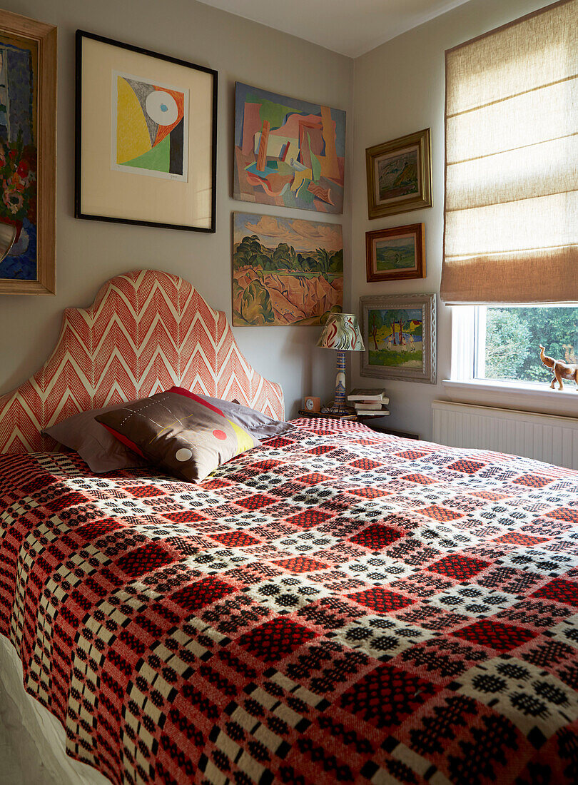 Gemusterte Decke und Kunstwerk mit Raffrollos im Schlafzimmer eines Hauses in London, England, Vereinigtes Königreich