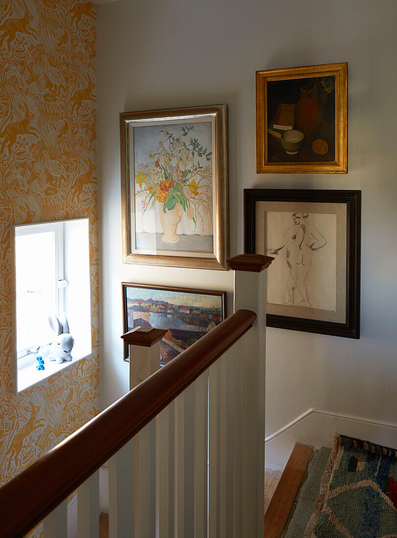Artwork collection with uncurtained window in staircase of London home, England, UK