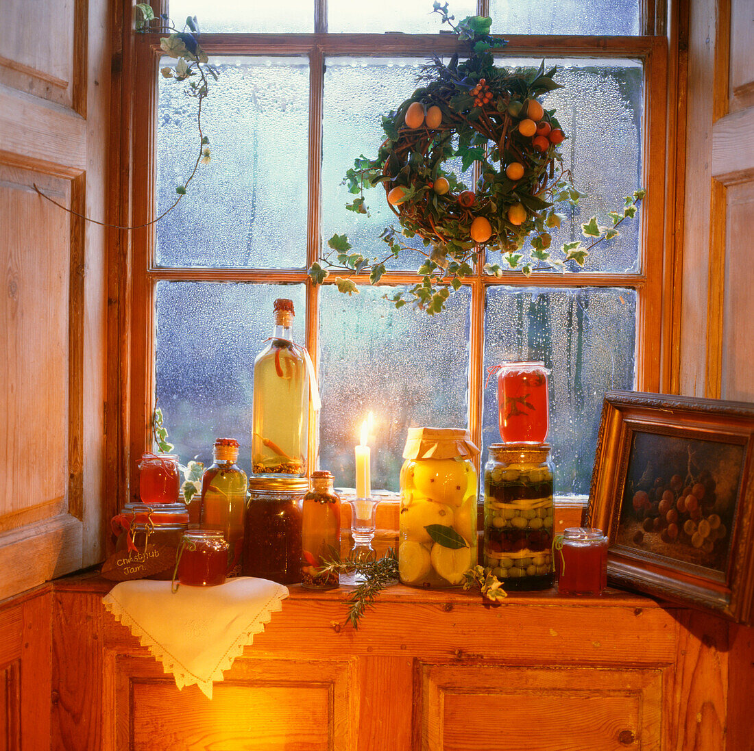 Beschlagenes Fenster an einem Winterabend mit eingelegtem Gemüse und Weihnachtsschmuck