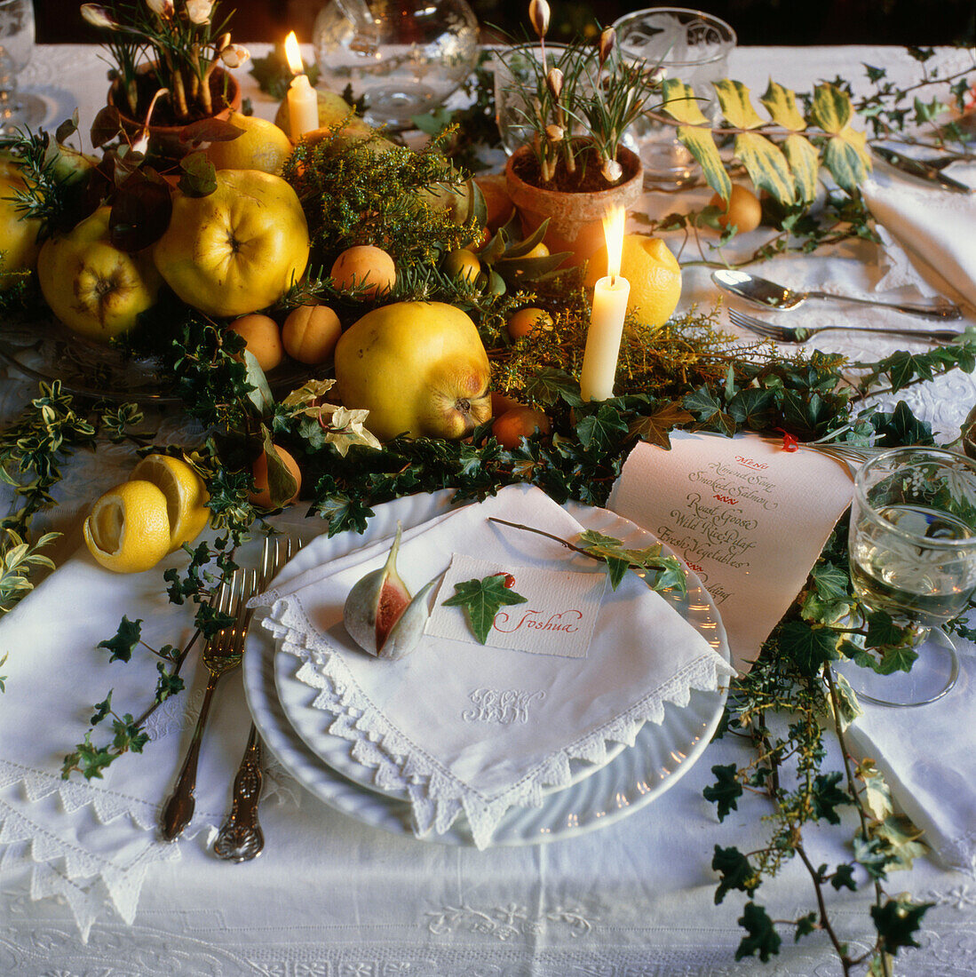 Herbstliche und winterliche Früchte auf dem Tisch mit Zweigen, Blättern und Kerzen
