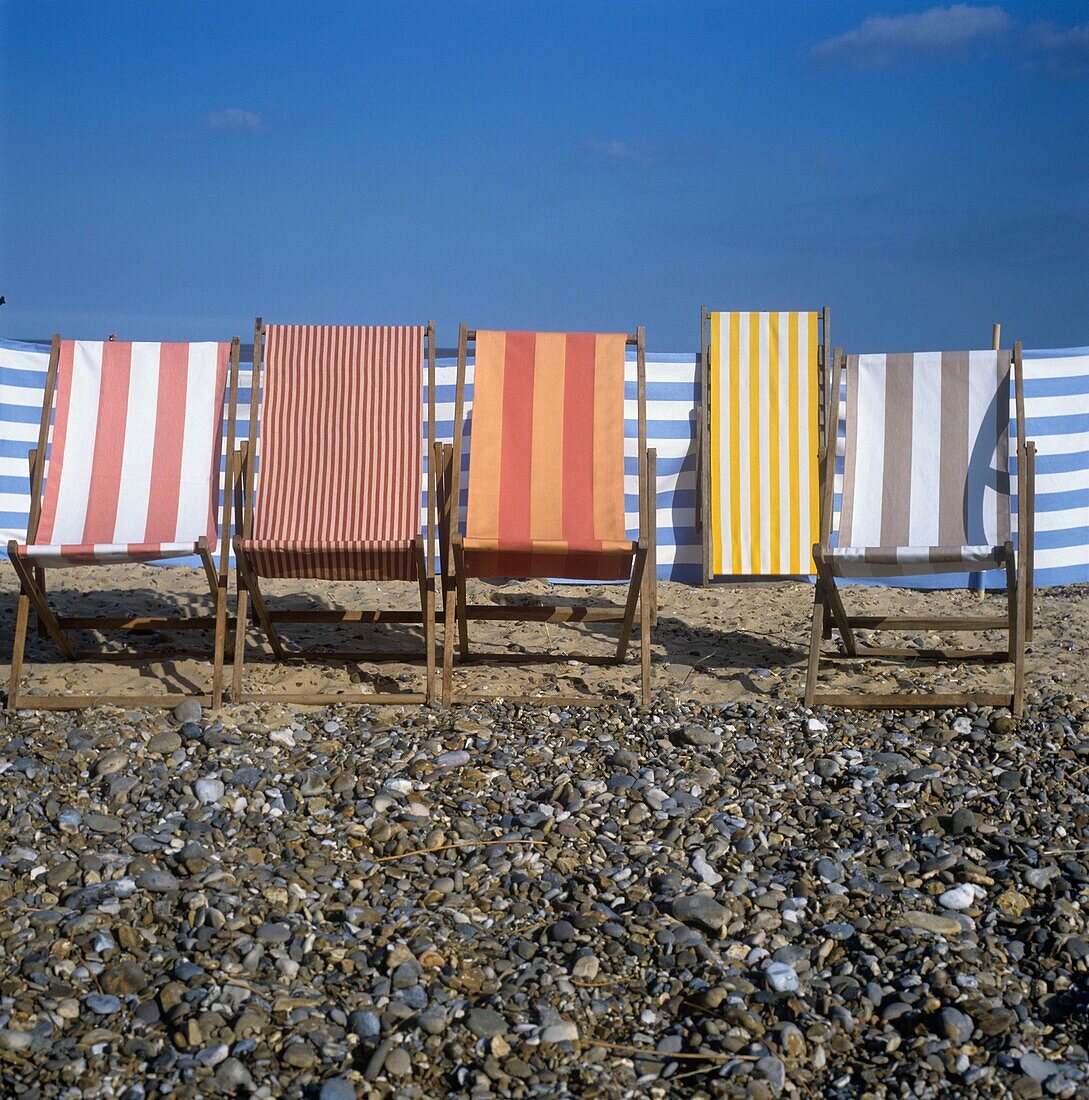 Striped deck chairs in row on pebble stone beach