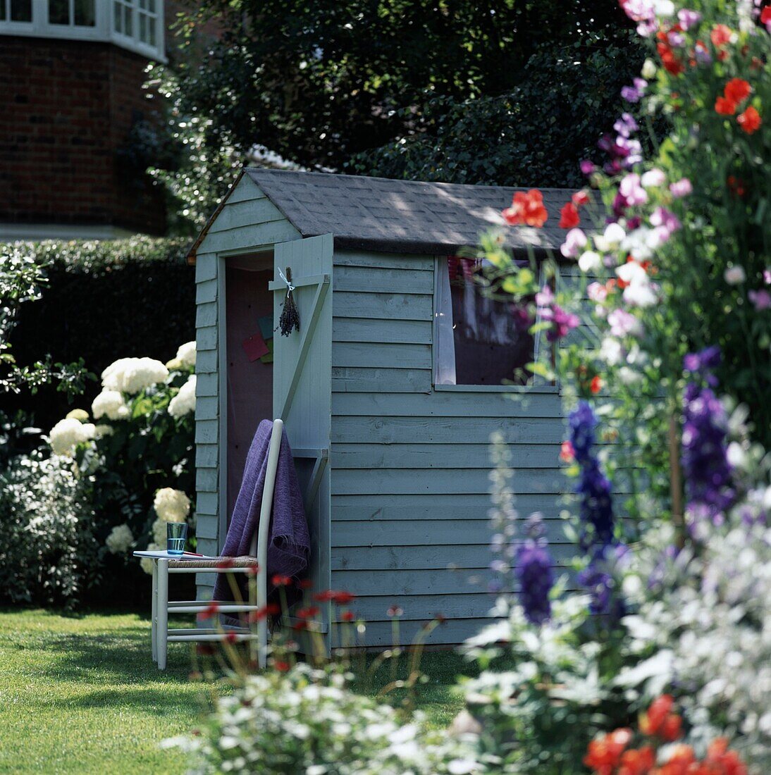 Wooden shed in garden among flowers