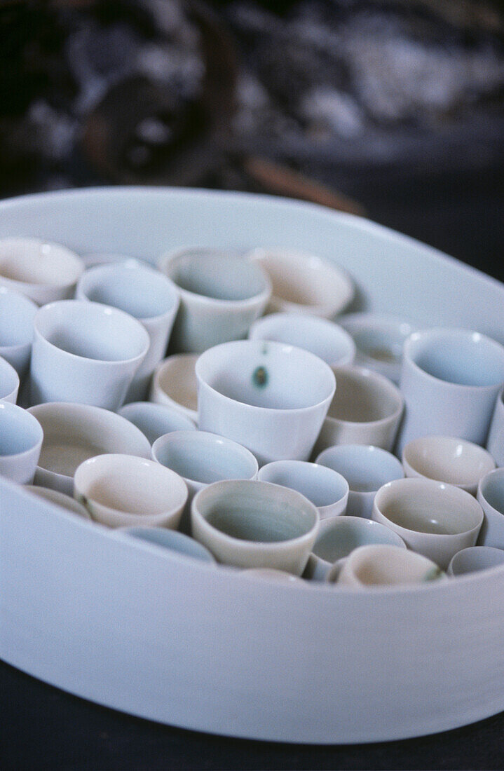 Auswahl an kleinen Sake-Tassen aus Porzellan in weißer Schale