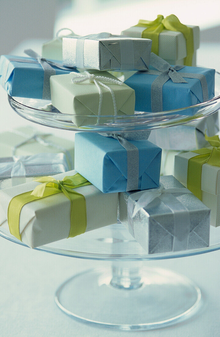 Gestufter Tortenständer aus Glas mit blauen und weißen Geschenkpaketen