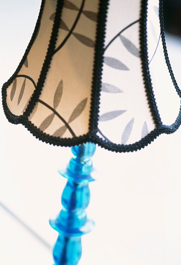 Gefranster Lampenschirm auf blauem Lampenfuß