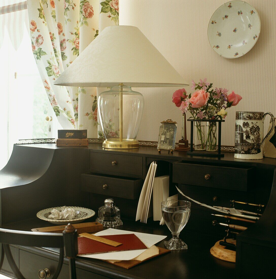 Schreibtisch-Detail mit Blumen und Wasserglas