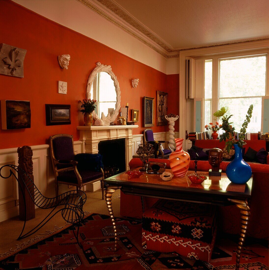 Beistelltisch mit Glasplatte in einem rot gestrichenen Wohnzimmer