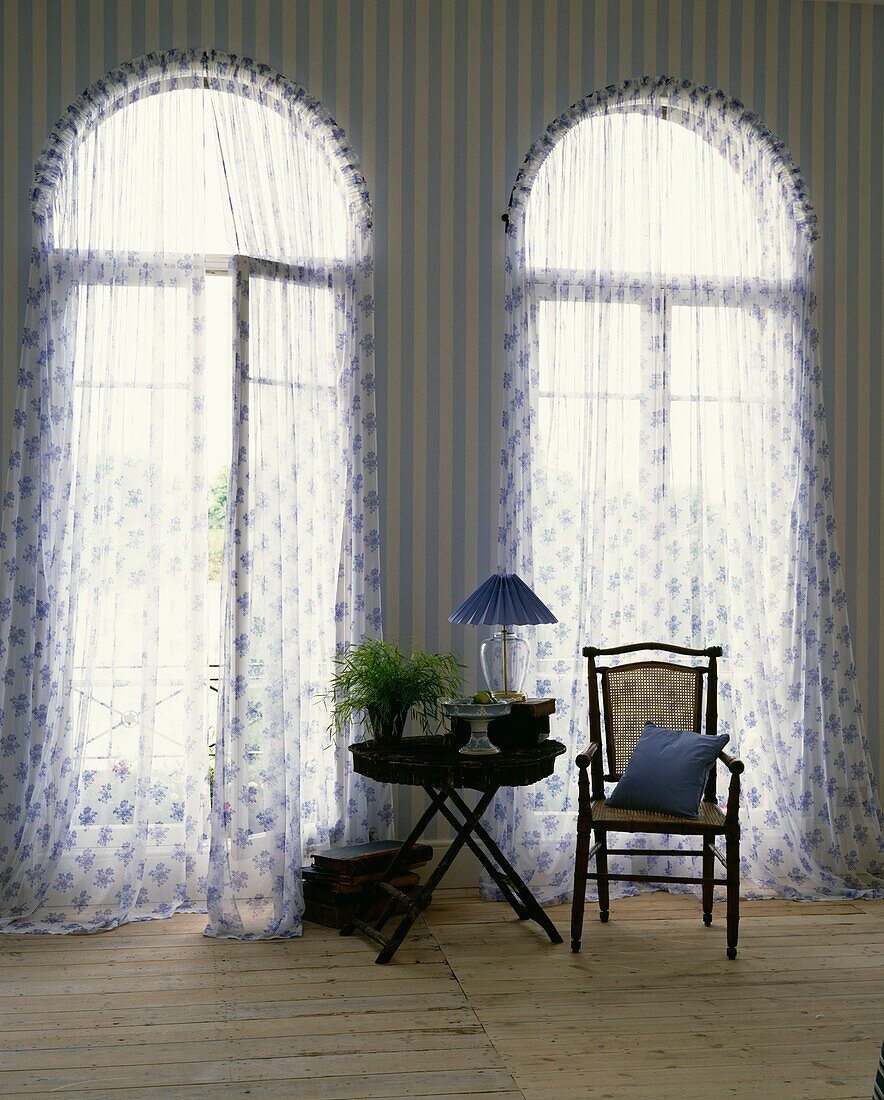 Folding table and chair at curtained and arched windows