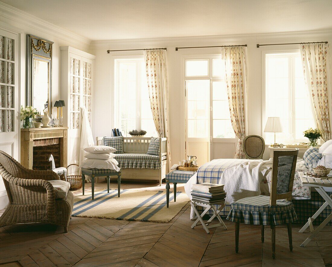 Sonnendurchflutetes Zimmer mit Einzelbett und Sitzecke am Kamin, ausgestattet mit kariertem Stoff