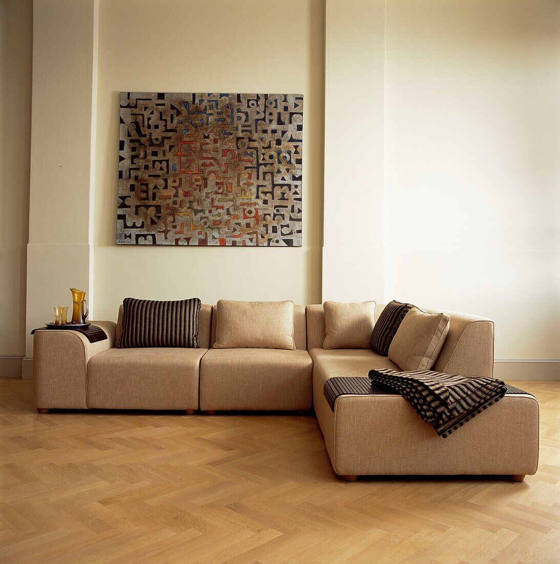 Modernes Kunstwerk über einem hellbraunen Sofa mit abgestimmten Kissen und Stoffen