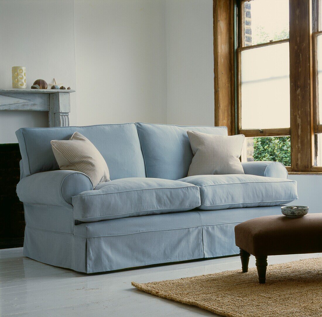 Pastellblaues Sofa mit Sprossenfenstern und Ottomanenhocker