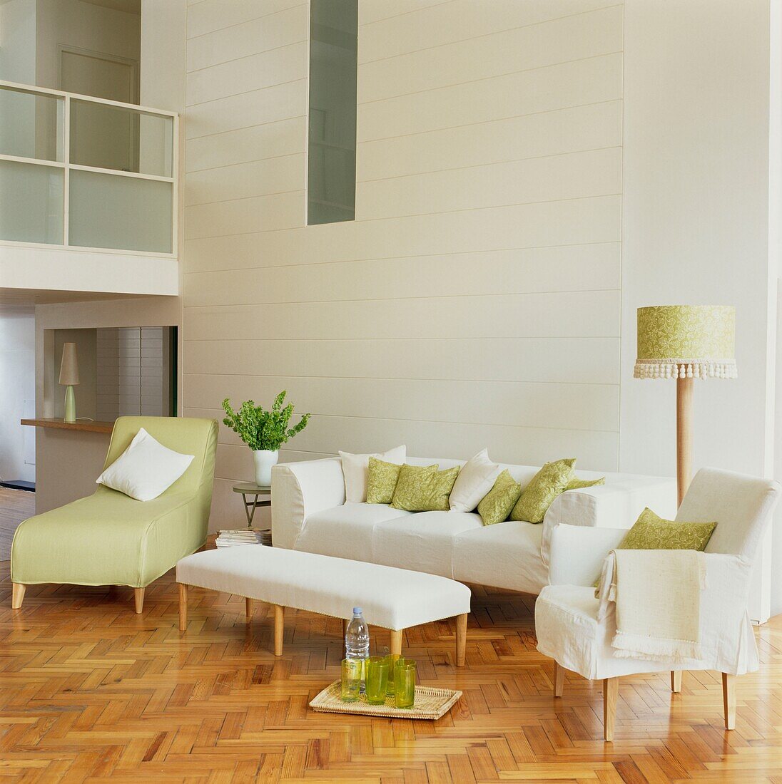 Weißes Sofa mit passenden Kissen und pastellgrüner Liege in einem umgebauten Lagerhaus mit hohen Decken und Parkettboden