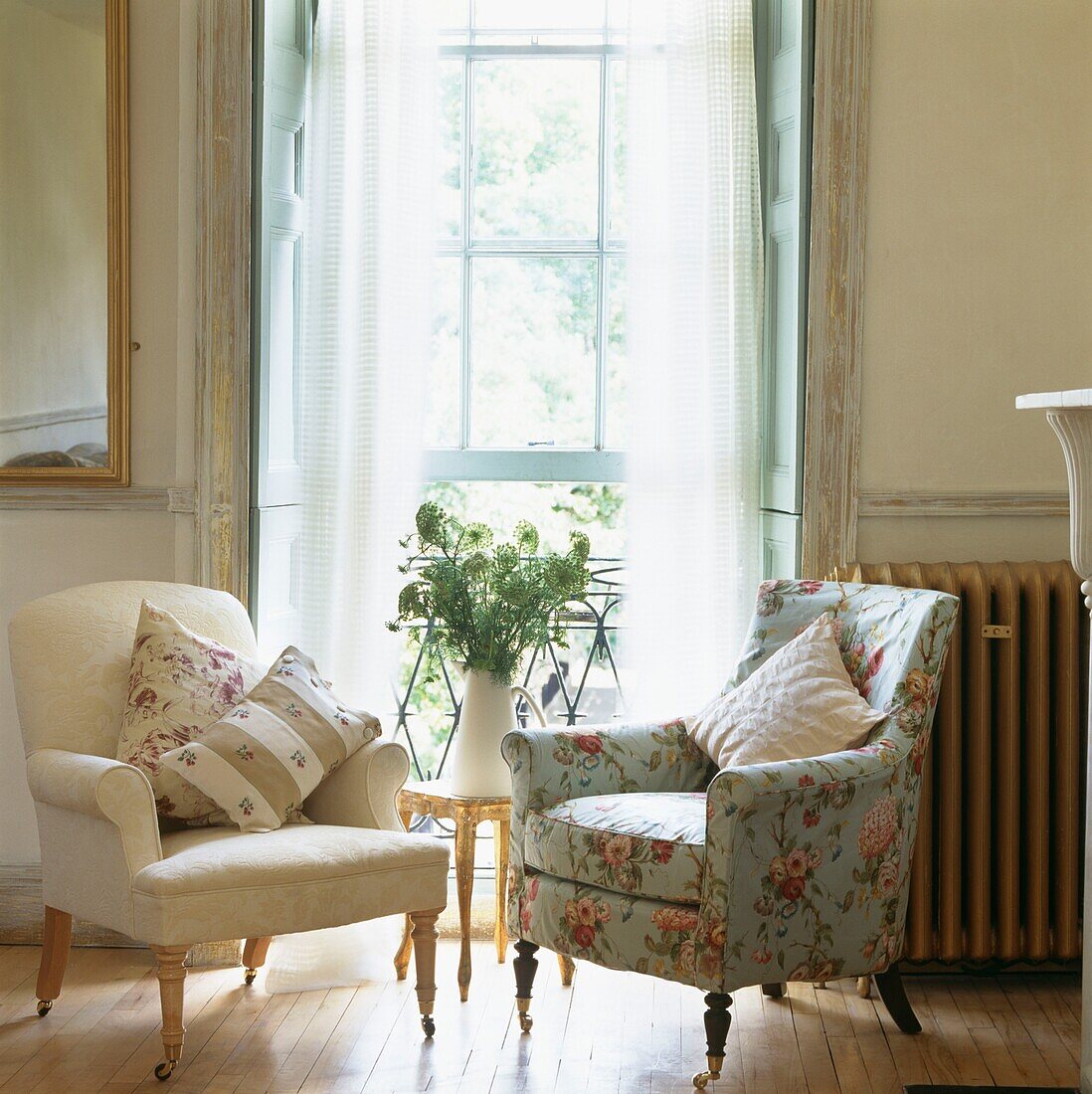 Sessel mit kontrastierenden Stoffen am offenen Fenster mit Farn-Arrangement