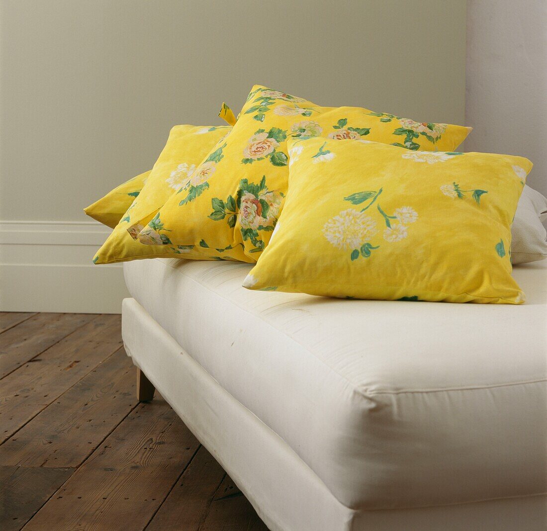 Yellow floral cushions on cream daybed with exposed floorboards