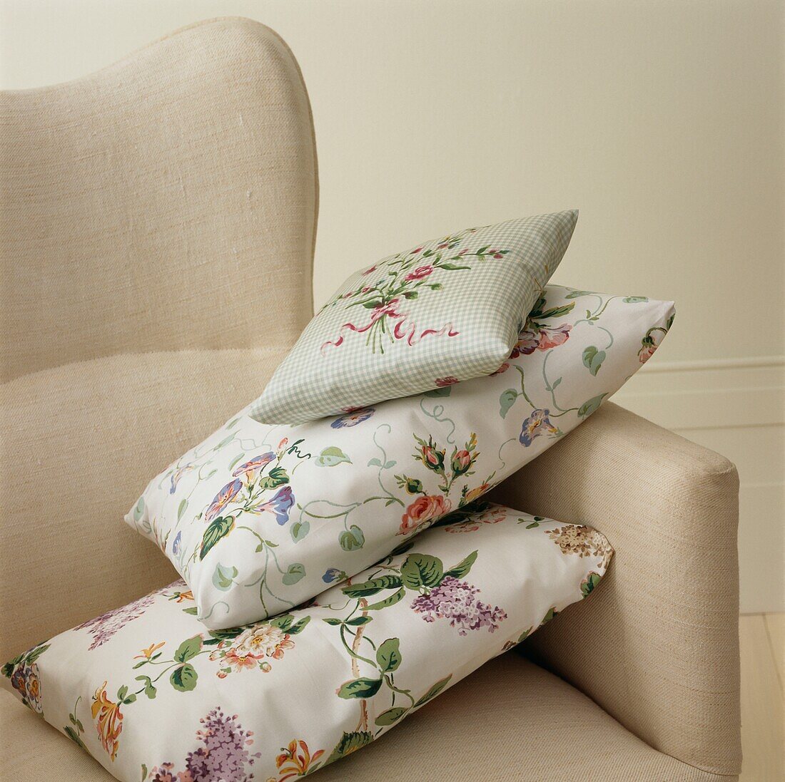 Three floral patterned cushions on a beige armchair