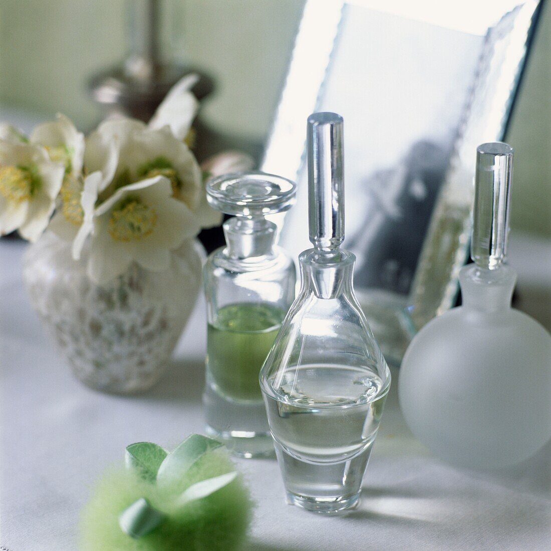Parfümflaschen und Blumenvase mit Spiegel auf dem Schminktisch