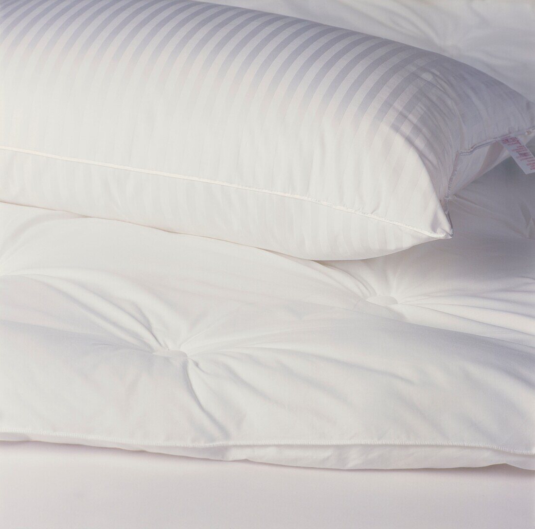 White striped pillow on uncovered duvet