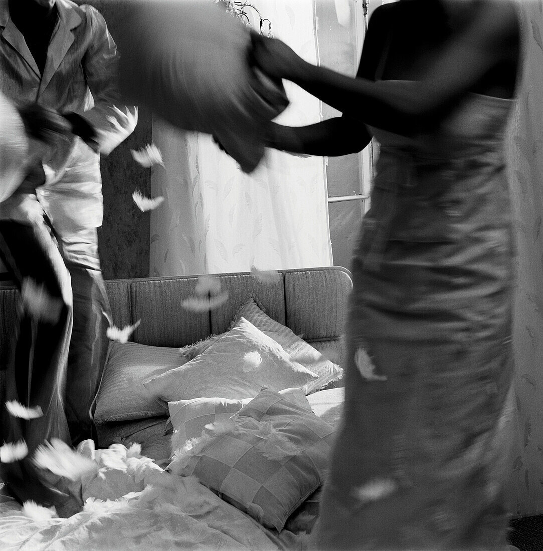 Couple have a pillow fight  on a bed in a bedroom